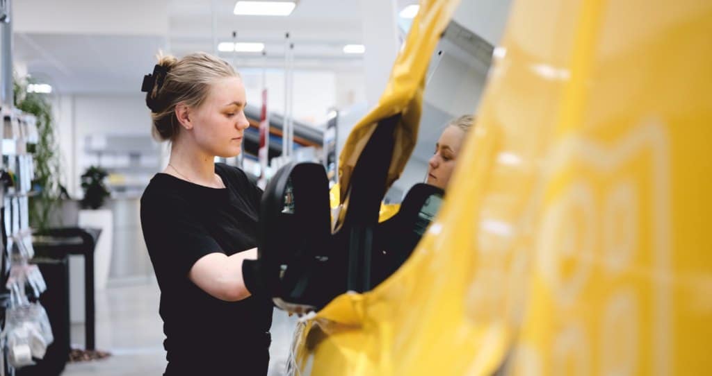 Montör som applicerar gul folie på ett fordon i verkstaden